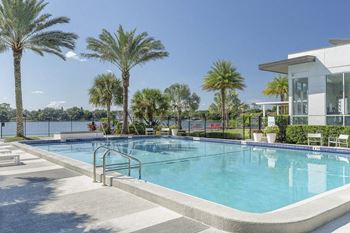 a swimming pool in front of a building with palm trees at Lakeside Villas, Orlando, FL 32817